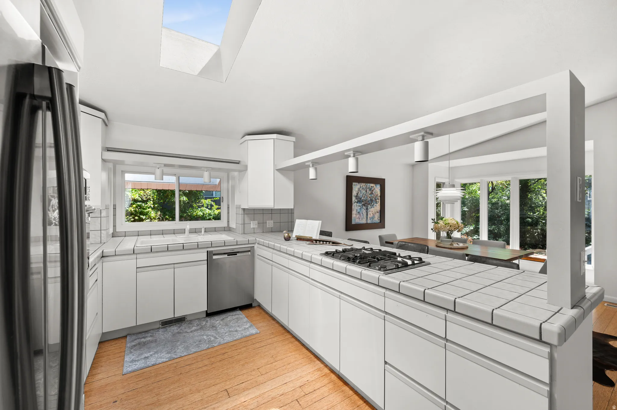 The open kitchen connects naturally to the dining area, with windows bringing the surrounding greenery into view.