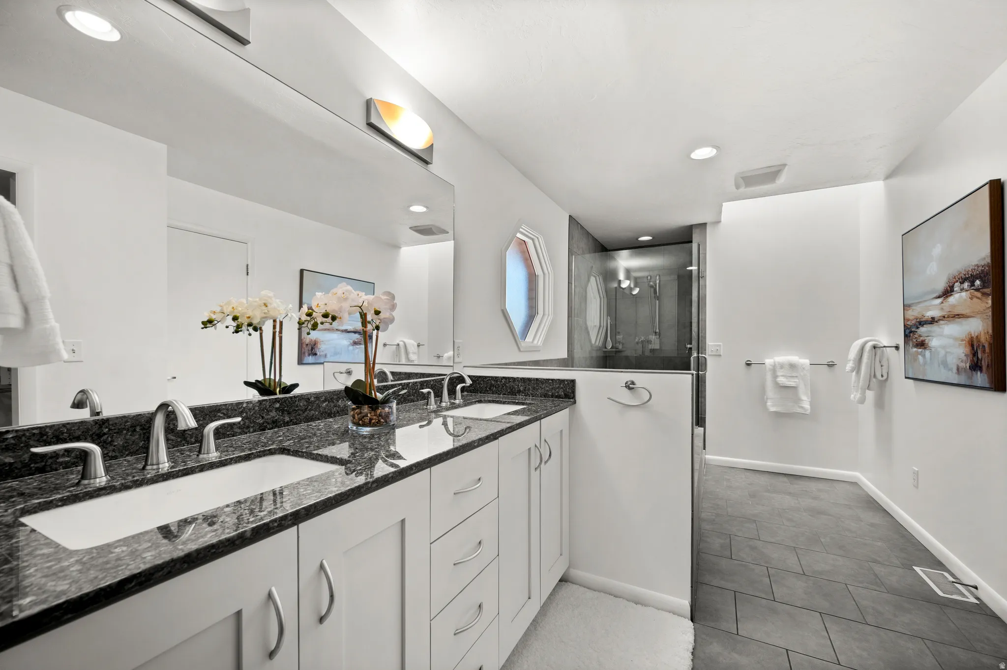 Spacious primary bath with double vanity, granite counters and a separate glass-enclosed shower.