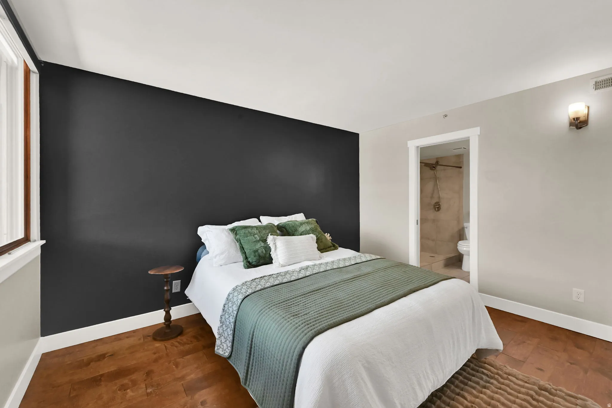 Primary bedroom. Wood-finish flooring, accent wall, white trim, recessed lighting, and wall-mounted light fixture