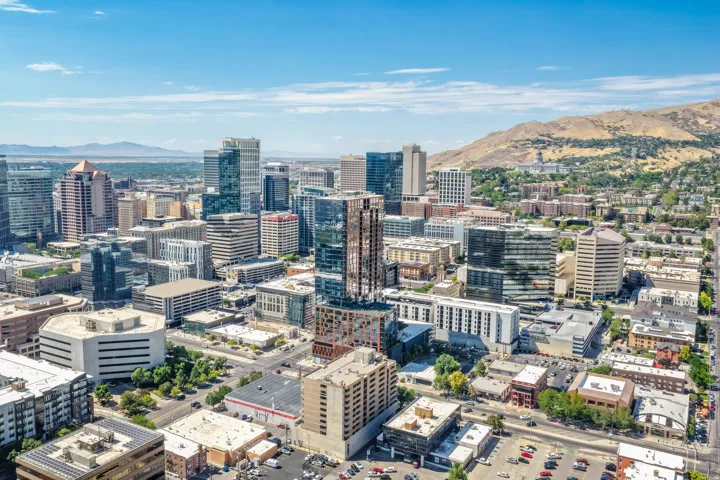 Expansive city skyline with diverse architectural styles, featuring contemporary high-rise buildings and a prominent mountain backdrop
