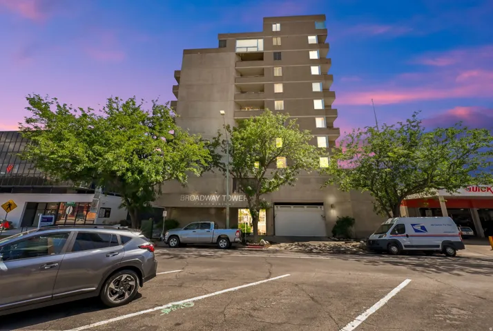 Modern multi-story building featuring concrete construction, multiple balconies, and integrated ground-level garage access