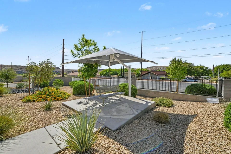 Shaded outdoor seating area with a built-in bench, concrete pad, and a metal-framed canopy