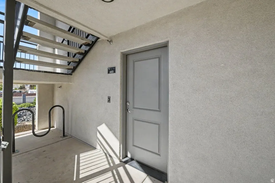Concrete exterior with a panel door and metal handrails