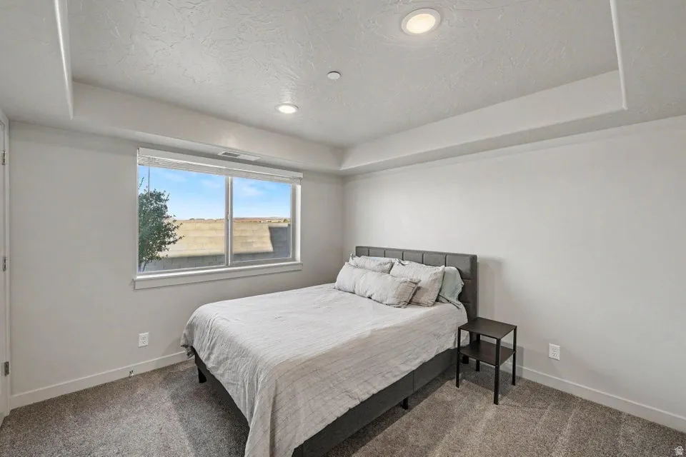 Recessed lighting, large window, neutral wall paint, gray carpet flooring, ceiling soffit