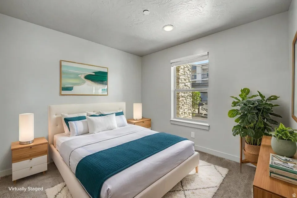 Recessed lighting, window with white trim, light gray wall finishes, carpeted flooring, and a stone exterior visible outside