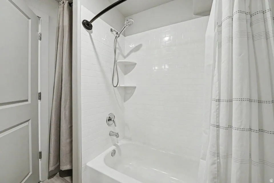 Bathtub with white subway tile surround, chrome fixtures, and a curved shower rod