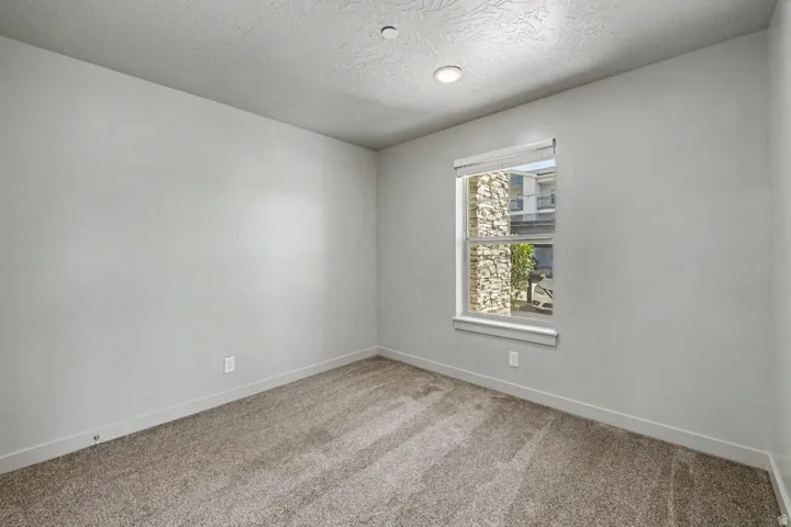 Neutral tone painted walls, textured ceiling, recessed lighting, carpet flooring, and a window with blinds