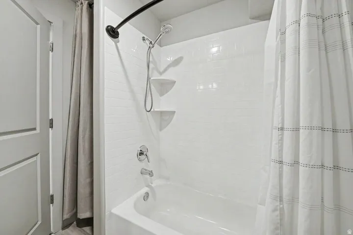 Bathtub with white subway tile surround, chrome fixtures, and a curved shower rod