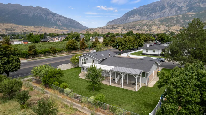Expansive green lawn, covered patio, mature trees, mountain scenery, and durable roofing
