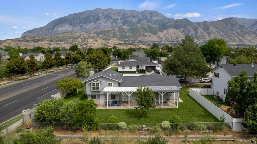 Expansive backyard featuring a manicured lawn, a large covered patio, and an open pergola
