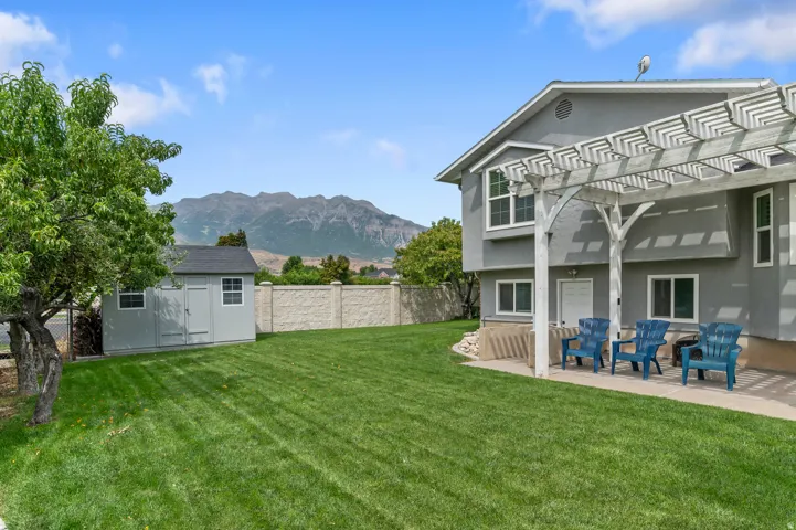 Expansive backyard featuring a manicured lawn, a detached storage shed, and a concrete patio with a decorative pergola