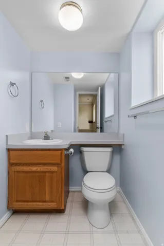 Single vanity with wood-finish cabinetry, integrated sink, and extended countertop