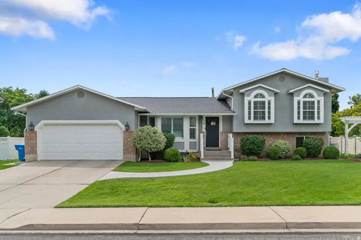 Split-level exterior featuring a two-car garage, brick accents, and dual arched windows