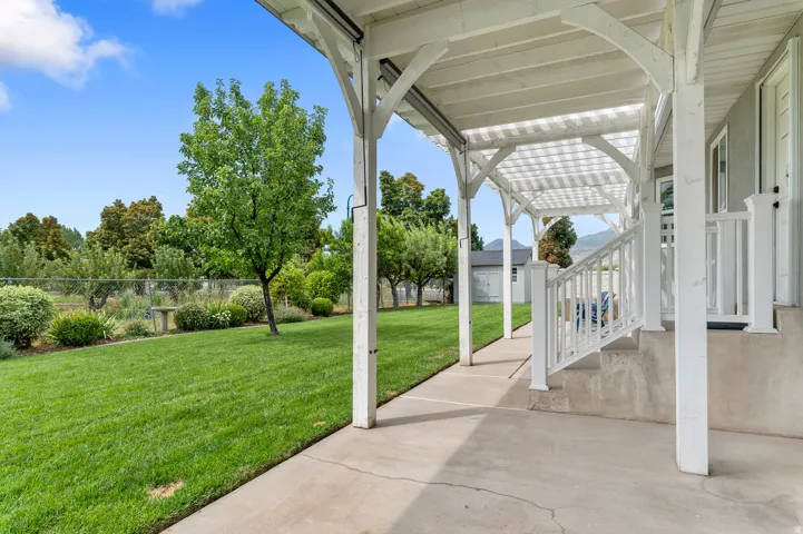 Covered porch with white wood-frame pergola and concrete flooring