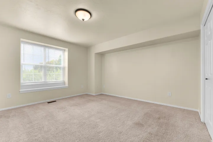 Recessed window with blinds, overhead flush mount lighting, light-colored walls, and neutral carpeting