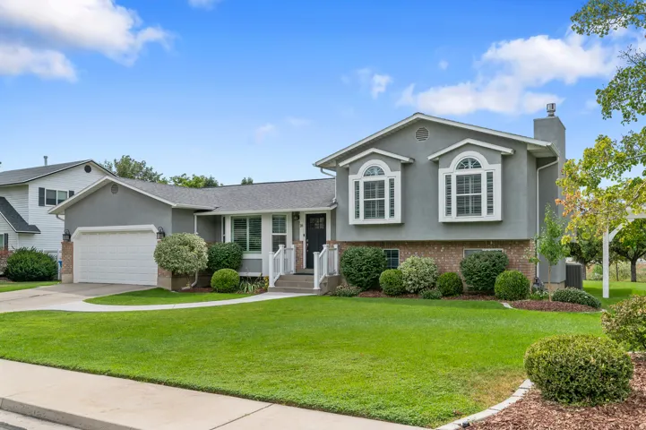 Gray stucco exterior with brick accents, arched bay windows, and a two-car garage