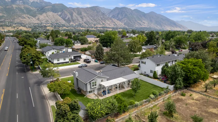Single-family residence with a gray exterior and white trim, featuring a covered patio, fenced backyard, and surrounding green space