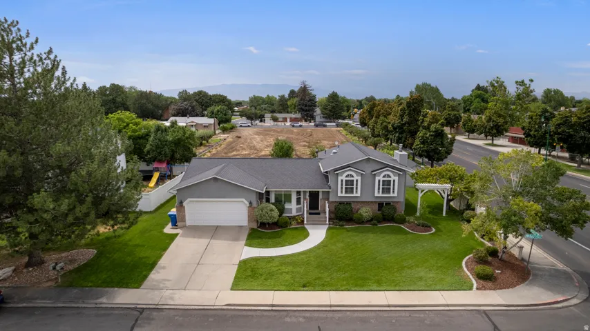 Two-story residence with a gray exterior, attached two-car garage, and a white arched trellis