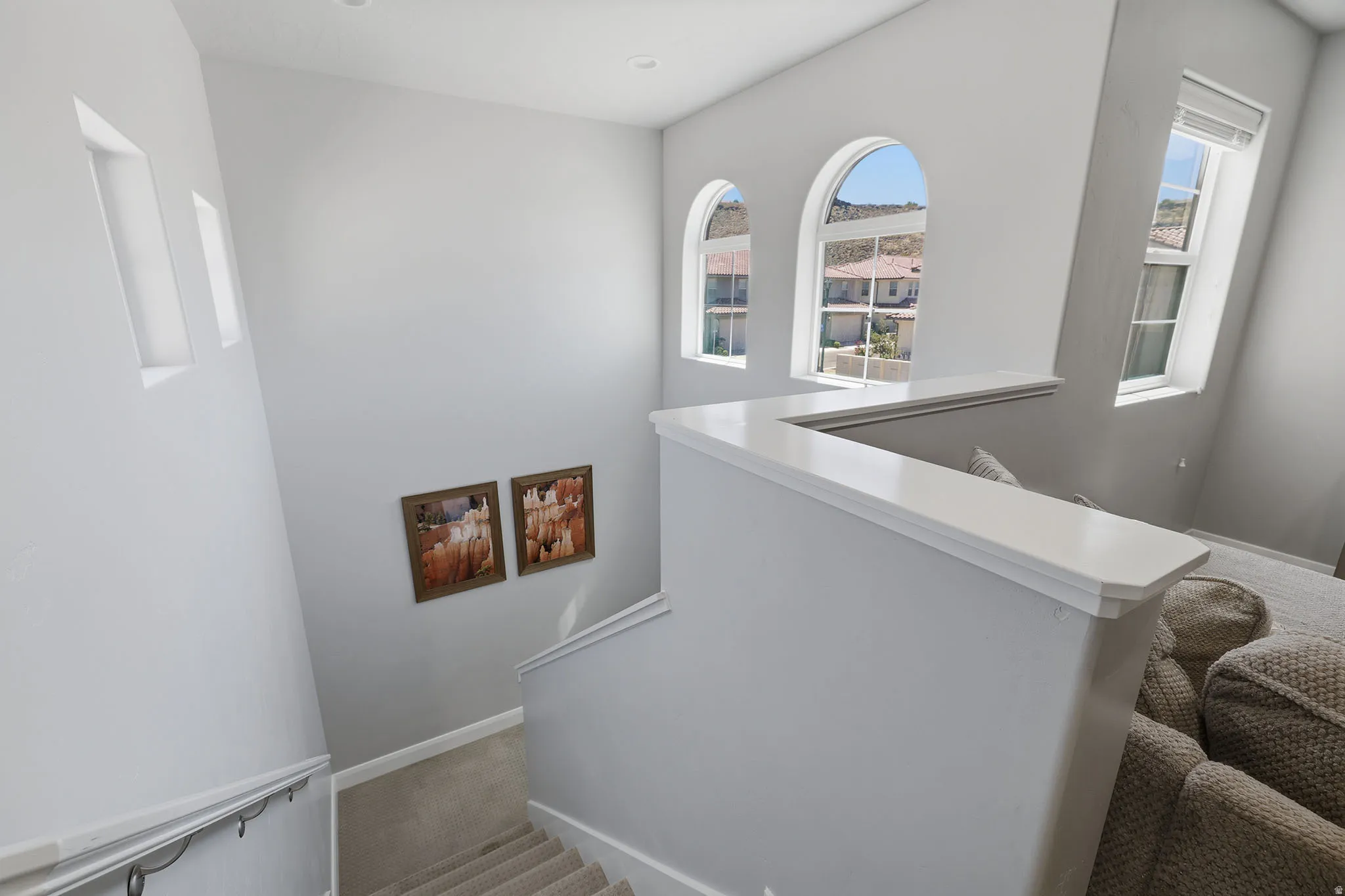Arch-top windows, recessed lighting, carpeted staircase, and white painted railings
