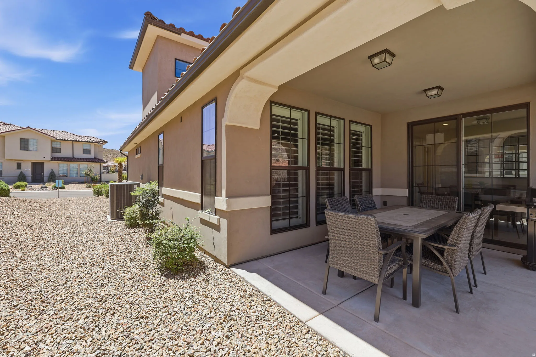 Covered patio with integrated lighting, a sliding glass door, and exterior windows with plantation shutters