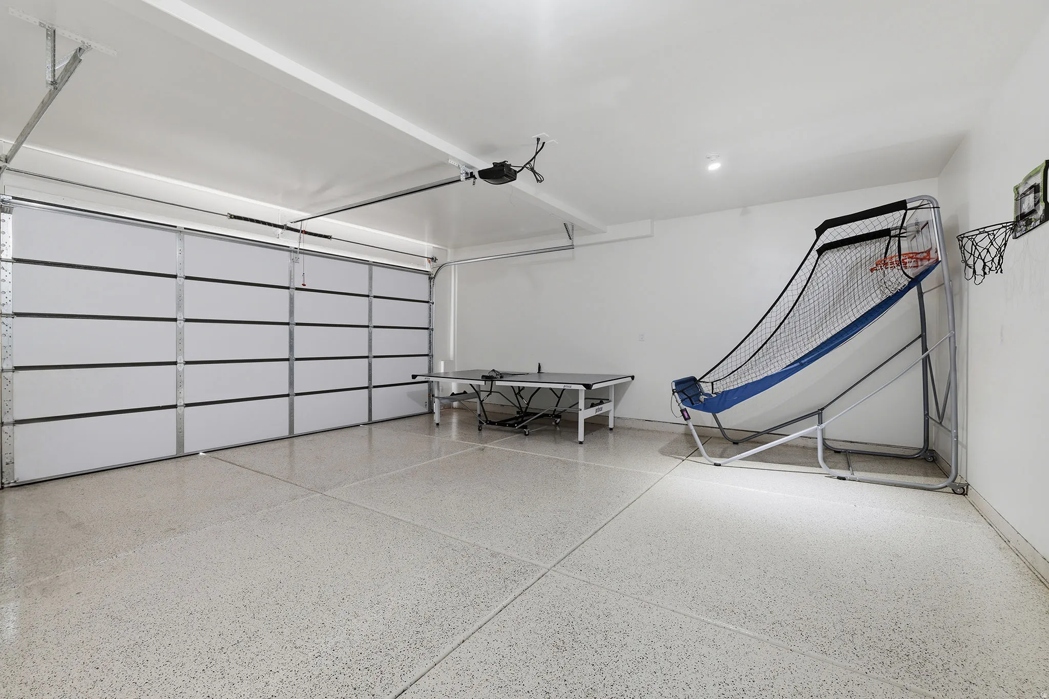 Garage with a large overhead door, finished walls, and speckled flooring