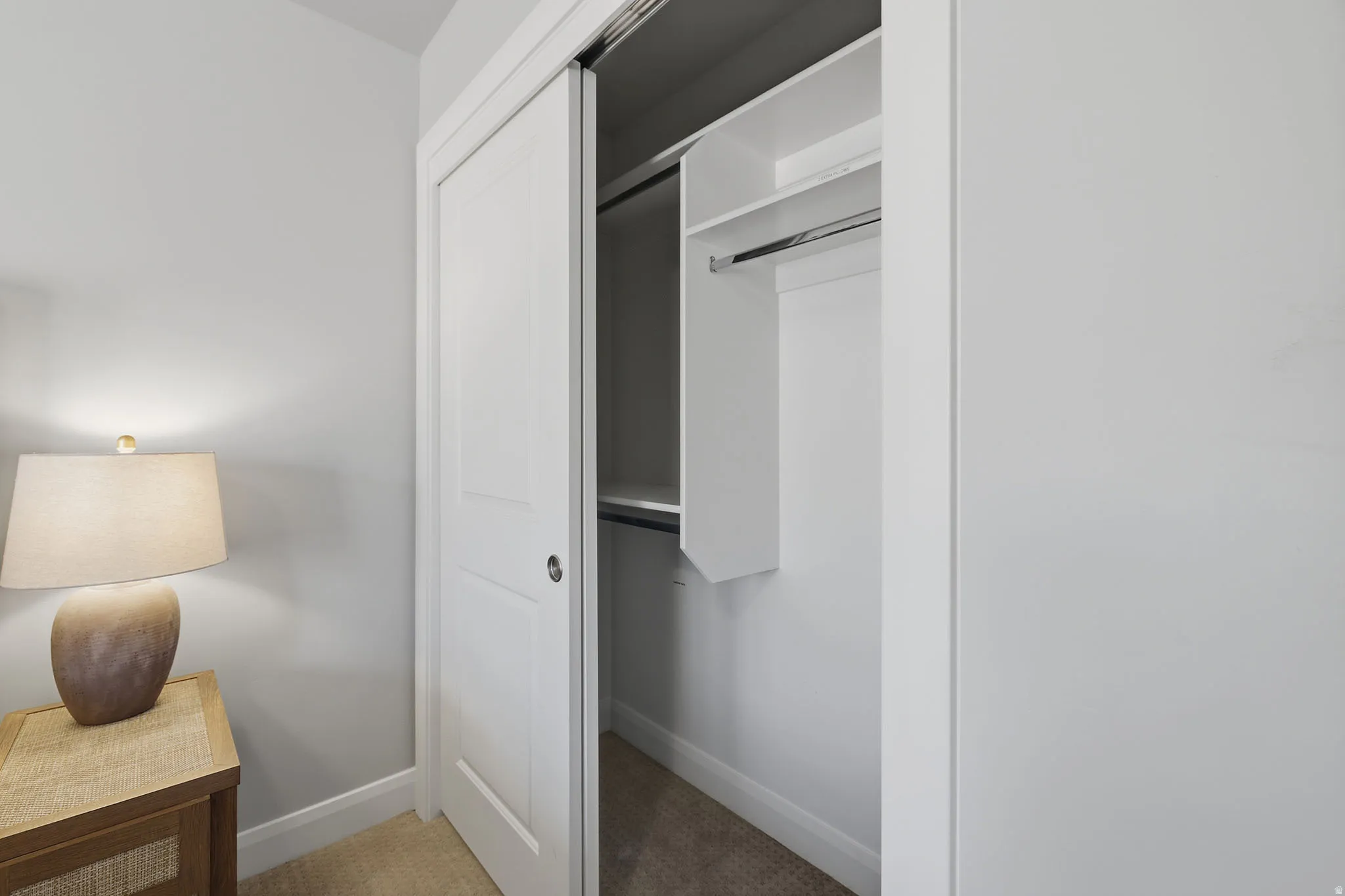 Sliding closet doors with white trim, built-in shelving, and a hanging rod