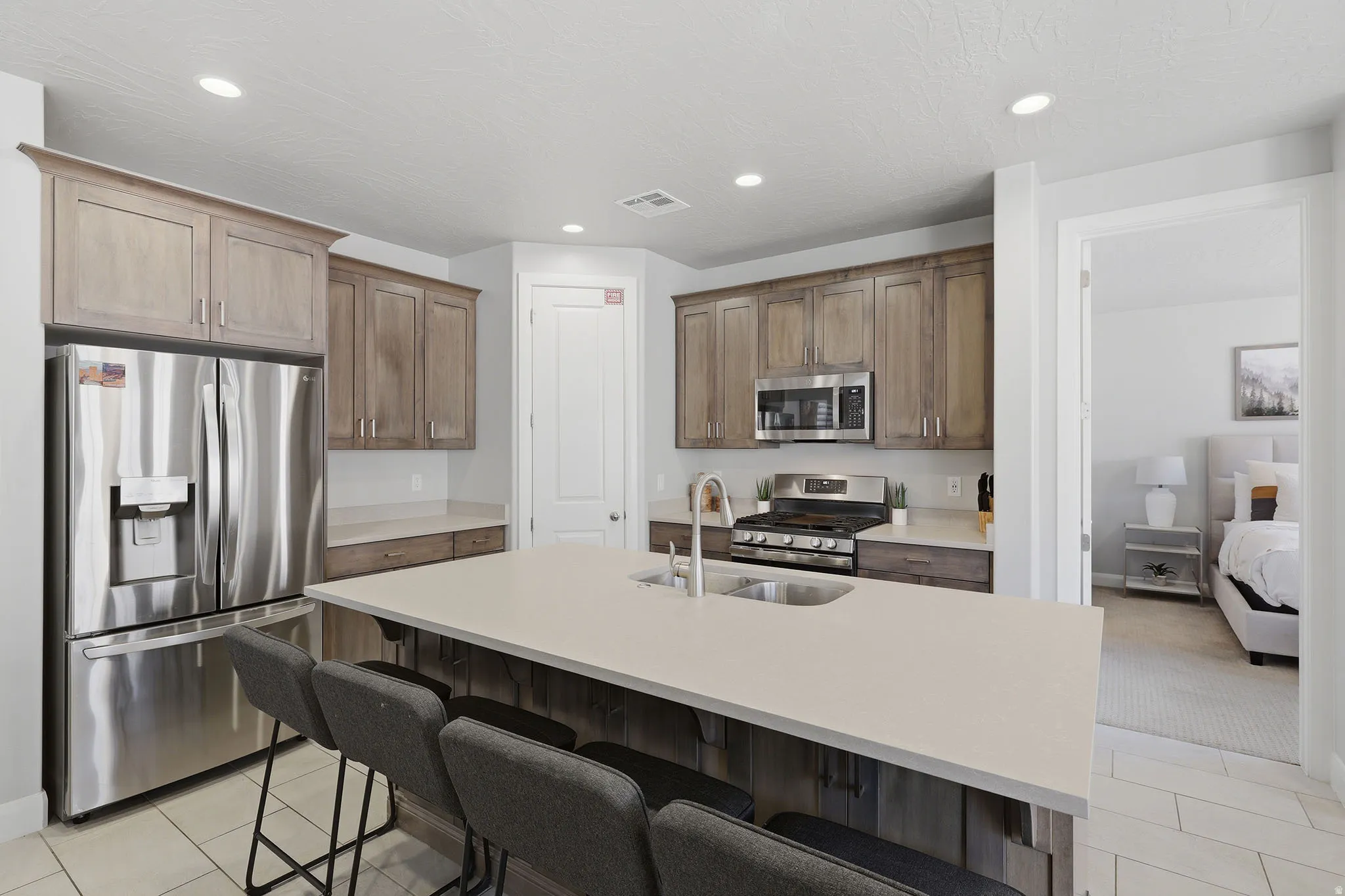Kitchen featuring stainless steel appliances, wood-finish cabinetry, a large center island with an integrated sink, and recessed lighting