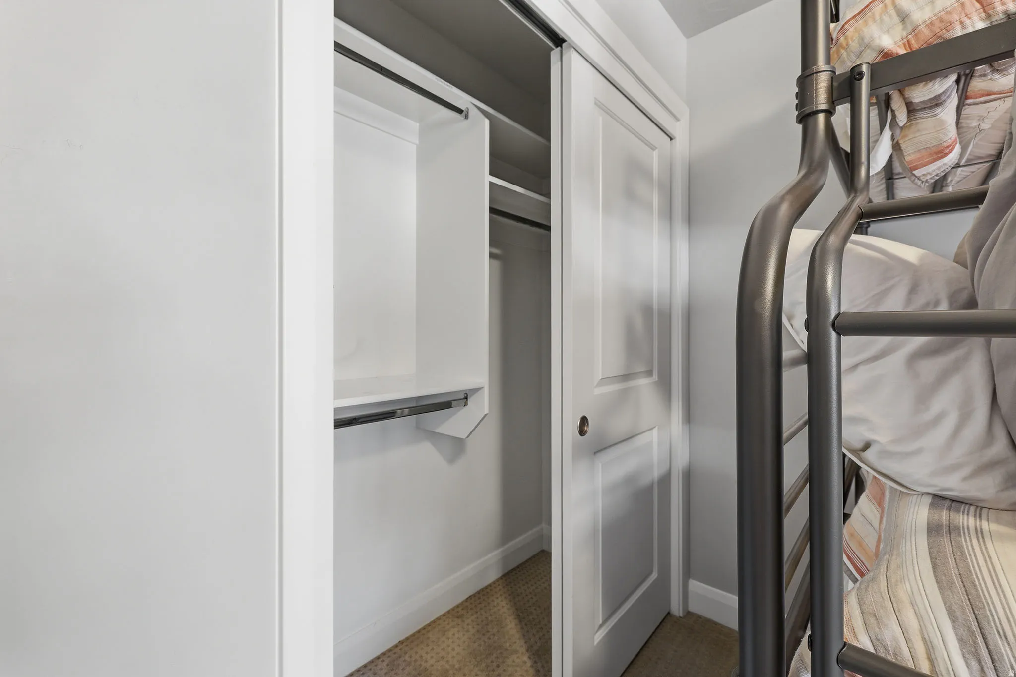 White bi-fold closet doors with integrated shelving and hanging rod