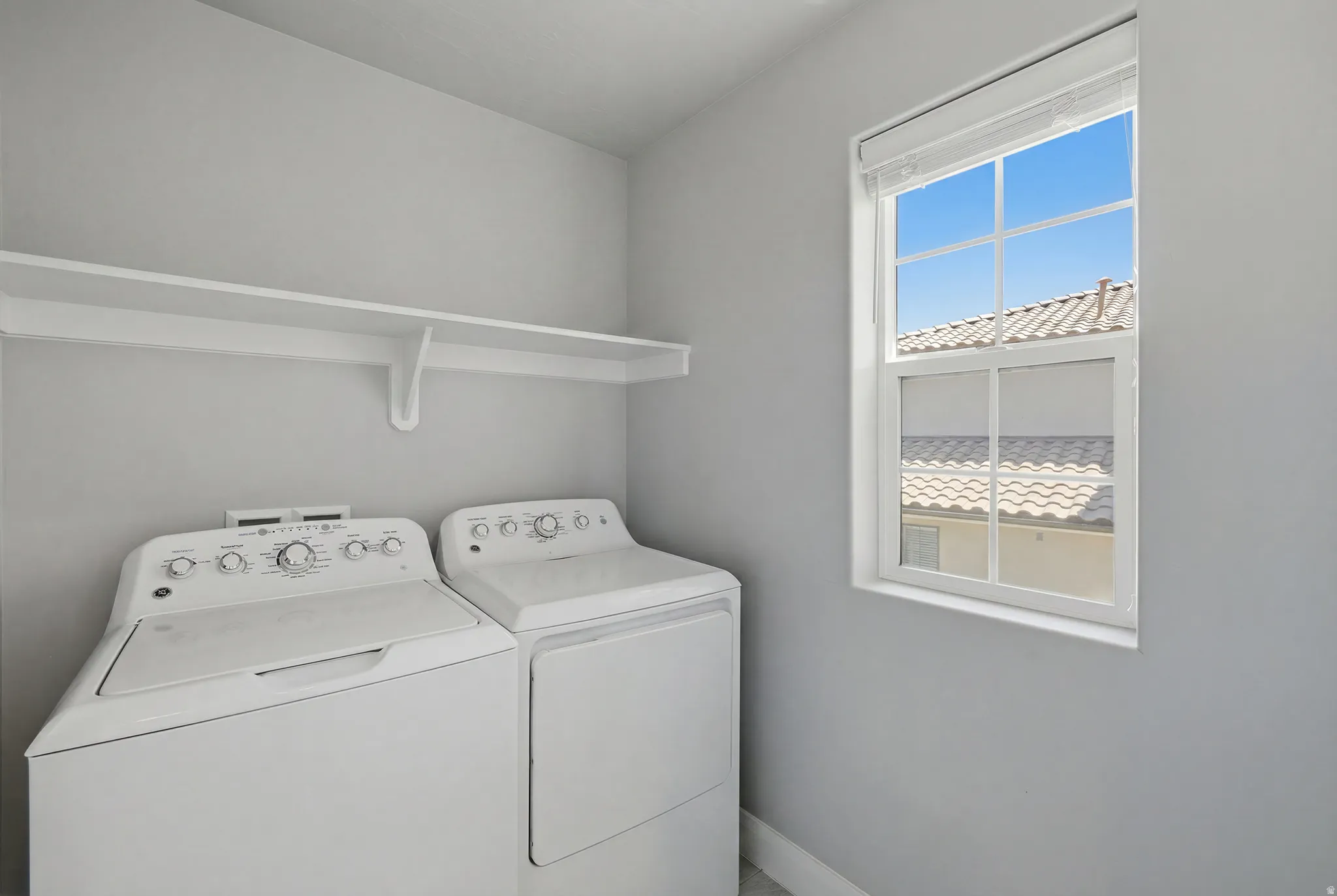 White wall-mounted shelving unit, double-pane window with white trim, and light gray wall paint