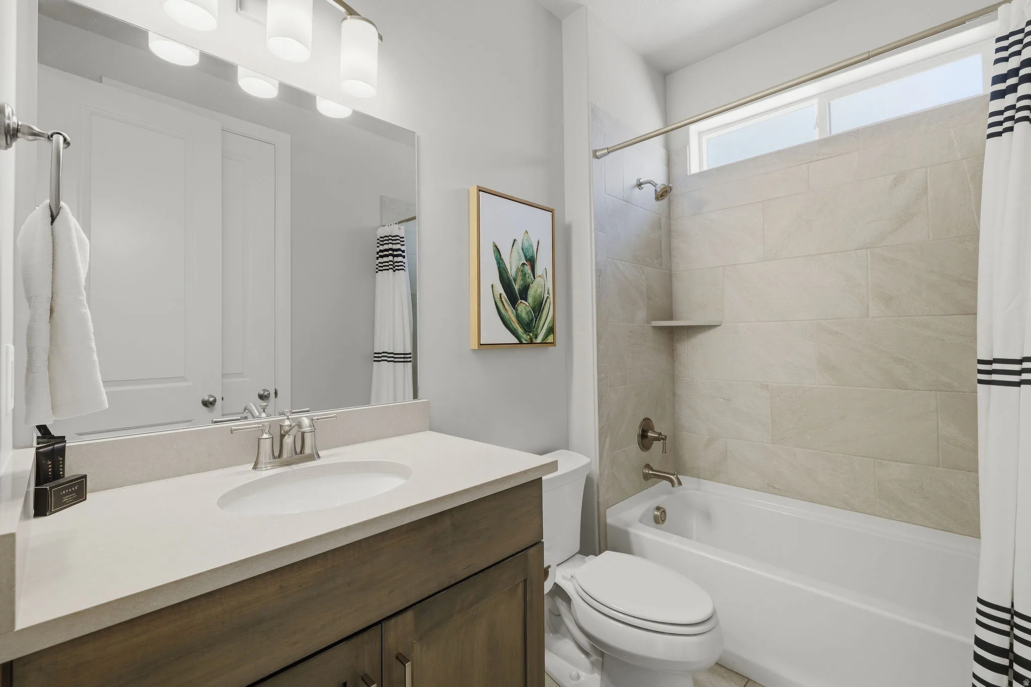 Vanity with light-toned countertop and integrated sink, wood-finish cabinetry, and brushed nickel fixtures