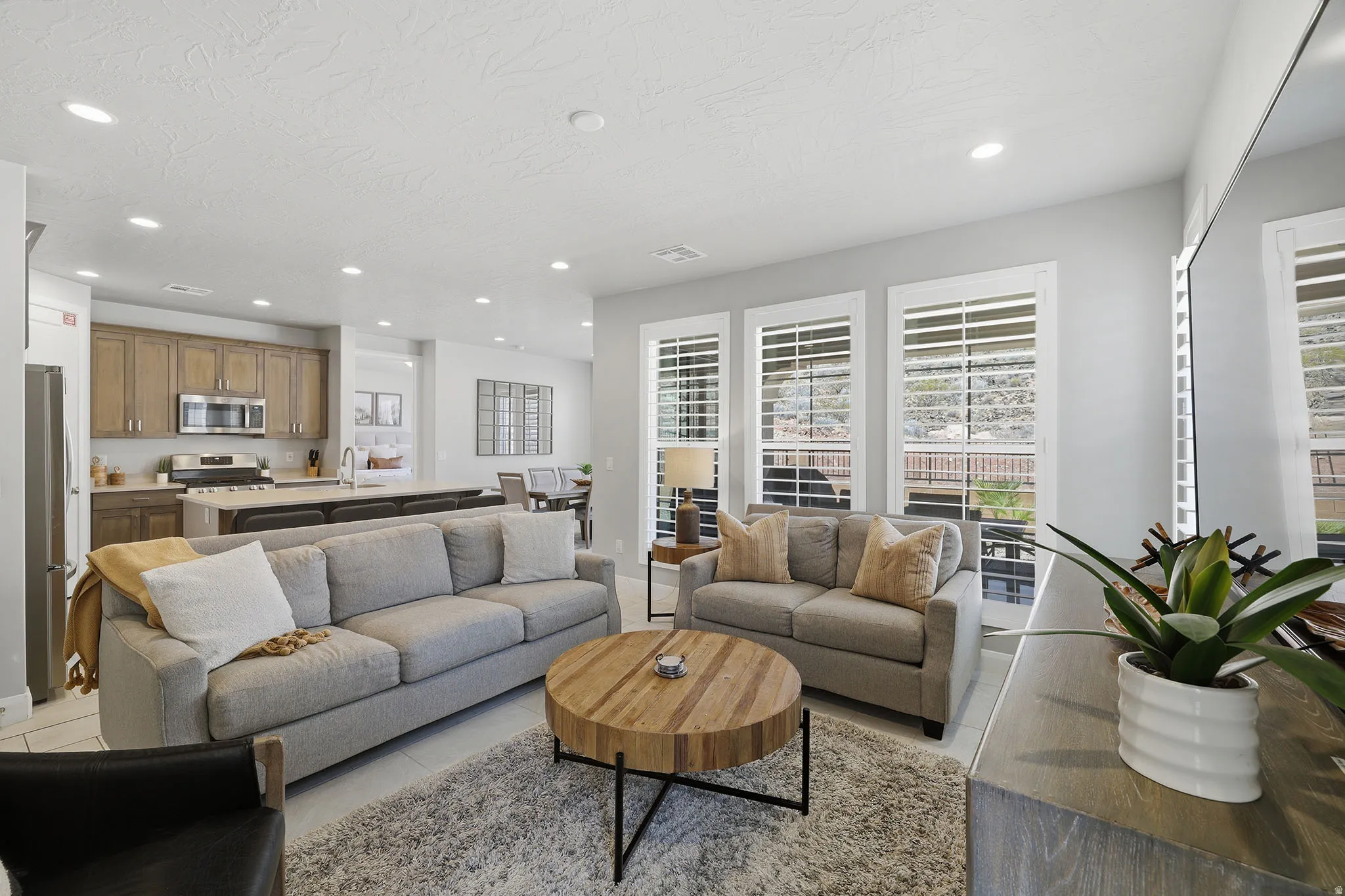 Open-concept living space with recessed lighting, wood-finish flooring, and white plantation shutters