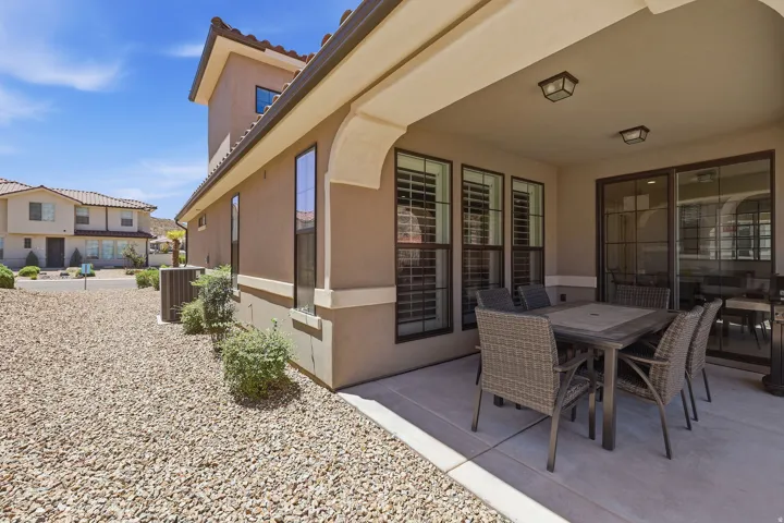 Covered patio with integrated lighting, a sliding glass door, and exterior windows with plantation shutters