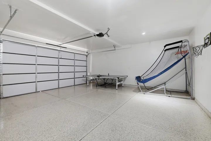 Garage with a large overhead door, finished walls, and speckled flooring