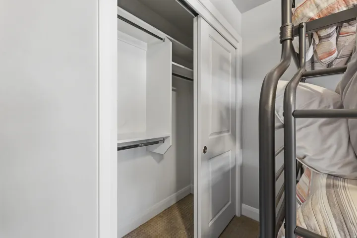 White bi-fold closet doors with integrated shelving and hanging rod