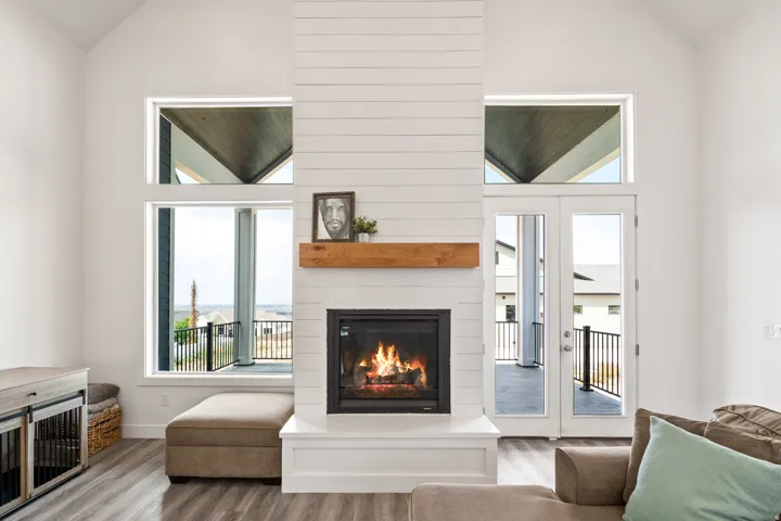 Vaulted ceiling, shiplap fireplace surround, wood-finish flooring, built-in fireplace, and expansive windows