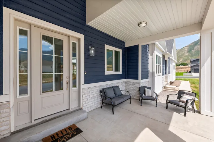 Covered concrete porch with dark blue horizontal siding, white brick accent, and a light-colored entry door with sidelights