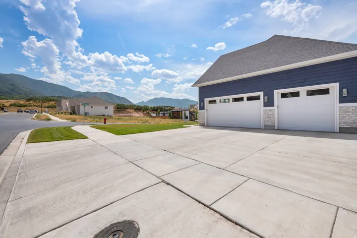 Concrete driveway with two garage doors featuring window panels, blue siding, and a stone facade