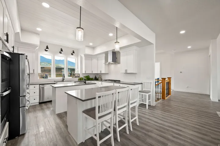Kitchen featuring white cabinetry, stainless steel appliances, a center island with bar seating, and wood-finish flooring