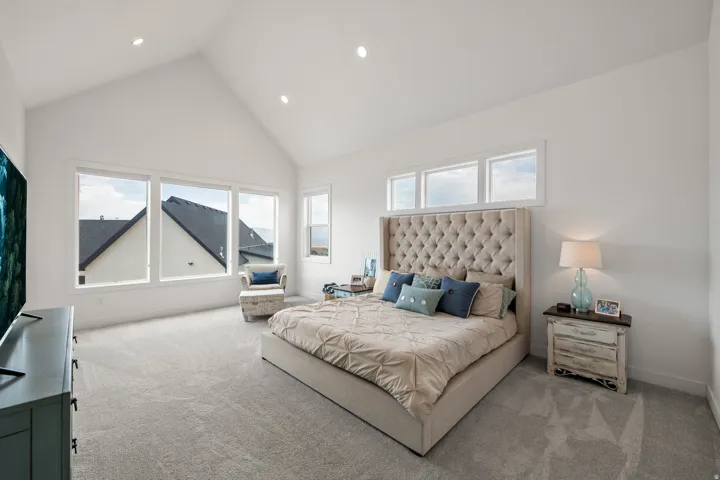Vaulted ceiling, recessed lighting, expansive windows, light gray carpeting, and neutral wall tones