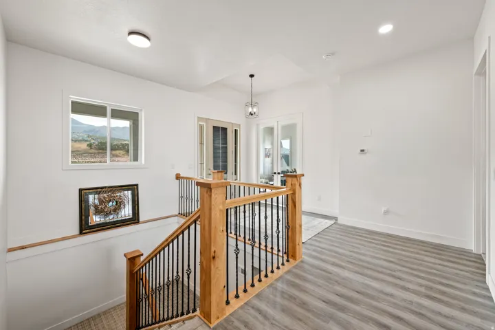 Hardwood stairs with wrought iron spindles, wood-finish flooring, recessed lighting, and a prominent window