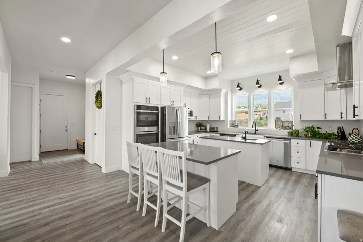 Kitchen featuring white cabinetry, gray countertops, a center island with seating, wood-finish flooring, and stainless steel appliances