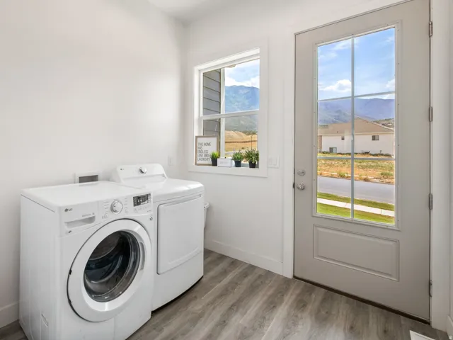 Laundry area featuring wood-finish flooring, a white paneled door with glass inserts, and a window offering a mountain backdrop