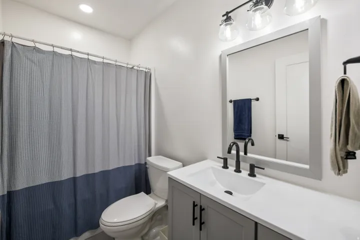 Vanity with integrated sink, matte black fixtures, framed mirror, and three-light sconce