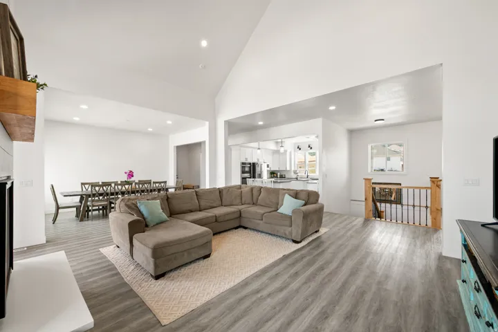 Vaulted ceilings with recessed lighting, light wood-finish flooring, and a natural wood staircase with metal balusters