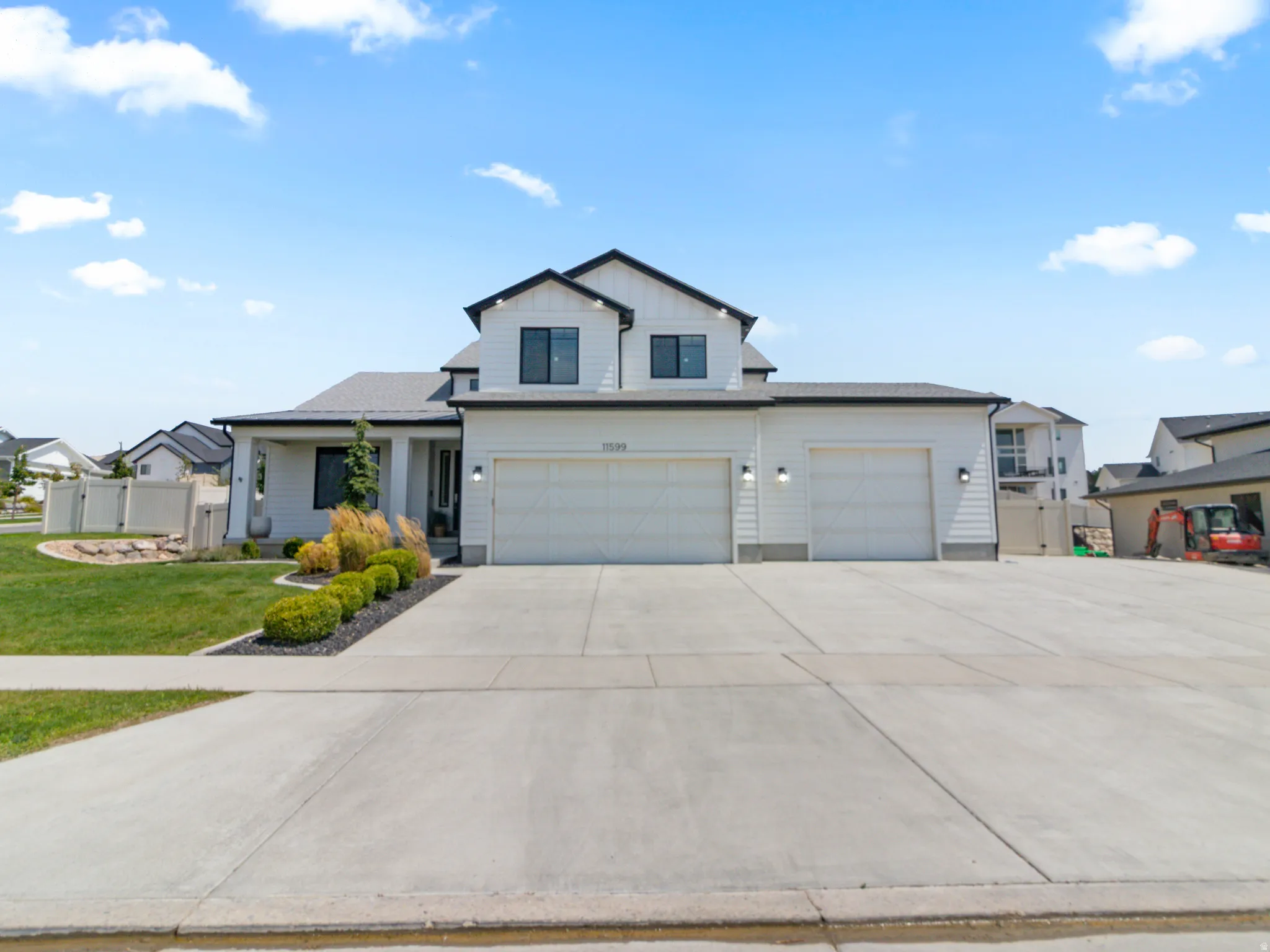 Contemporary exterior with white siding and black trim, featuring a 5-car garage, a covered entry, and a concrete driveway