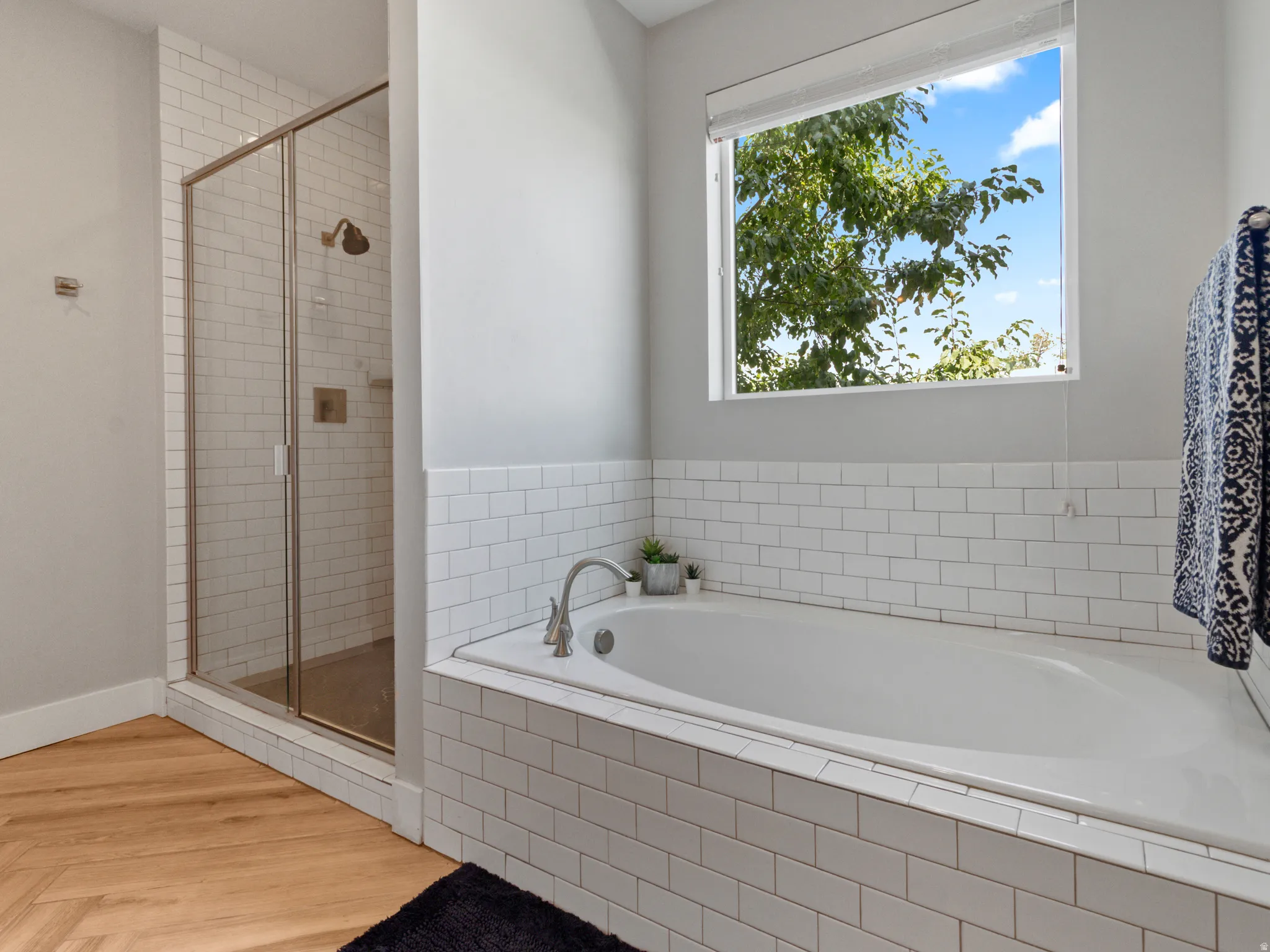 Walk-in shower with clear glass enclosure, subway tile surround, and brushed bronze fixtures