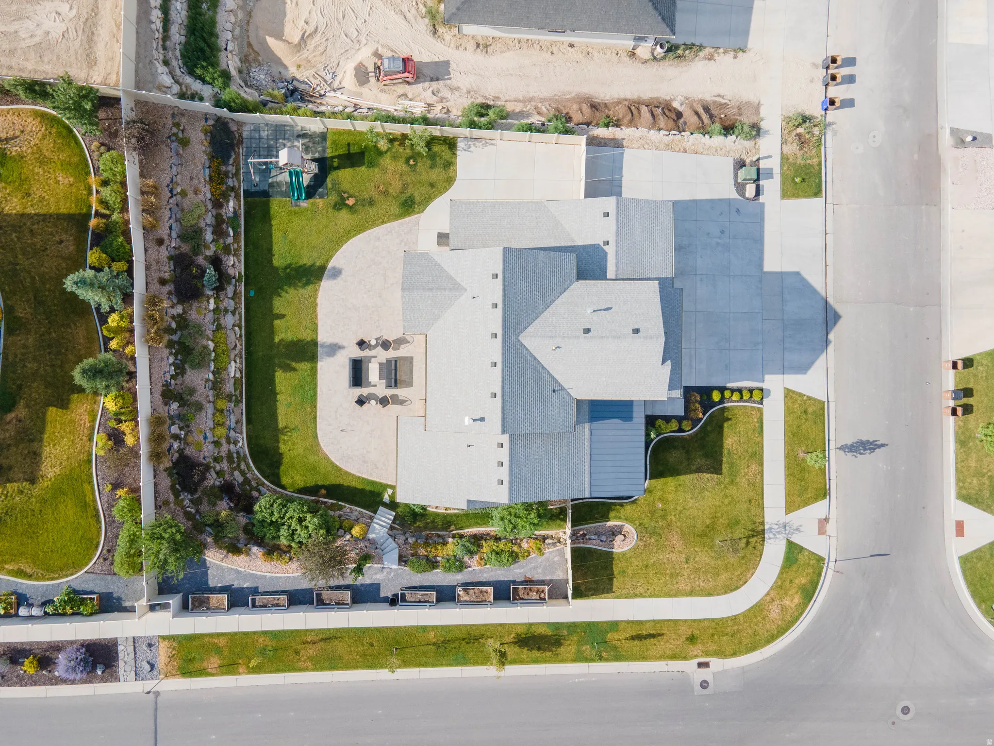 Expansive property featuring a multi-level roofline, extensive paved driveways, a large lawn area, and structured landscaping