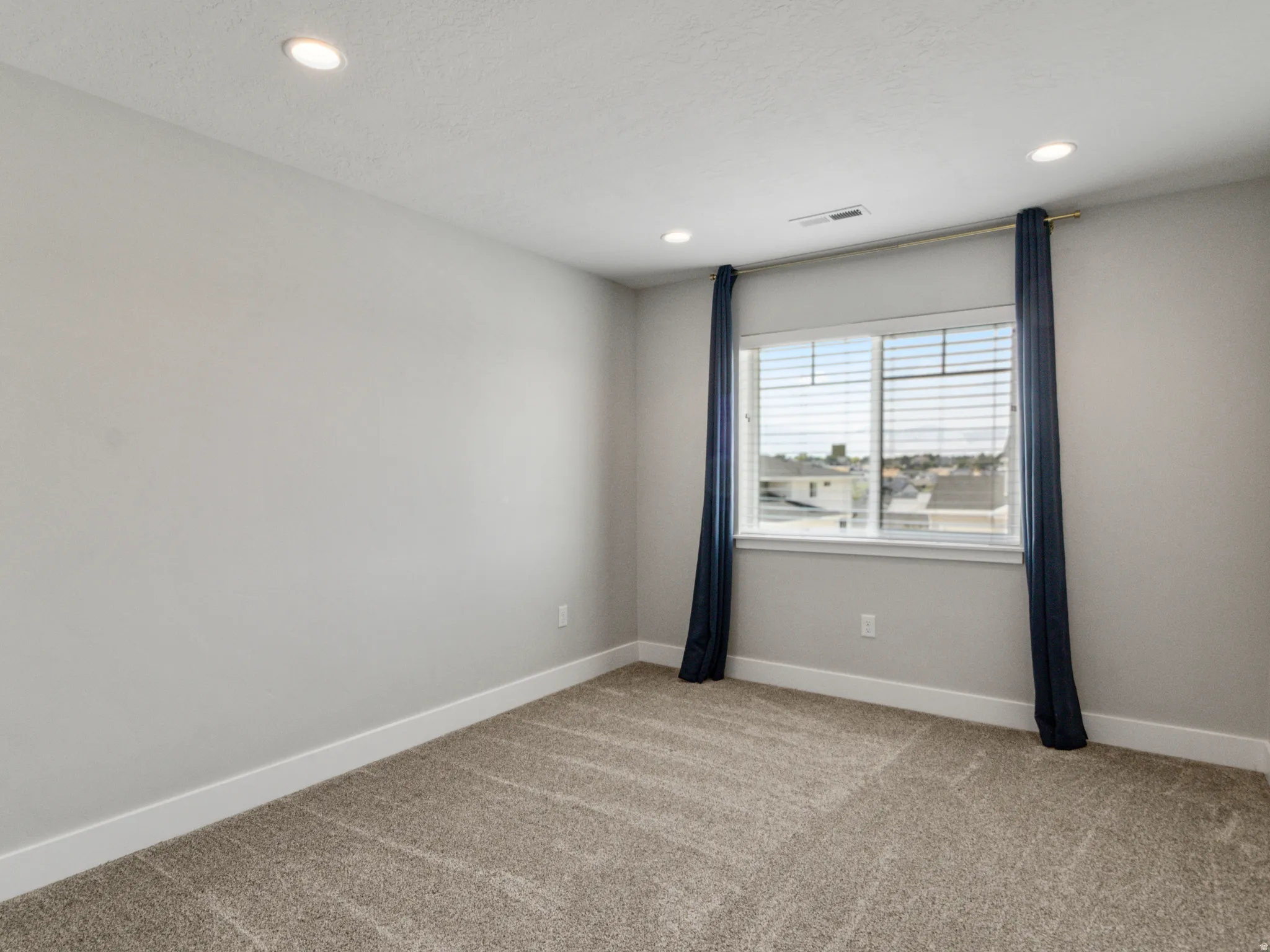 Recessed ceiling lighting, window with horizontal blinds, and neutral-toned wall paint