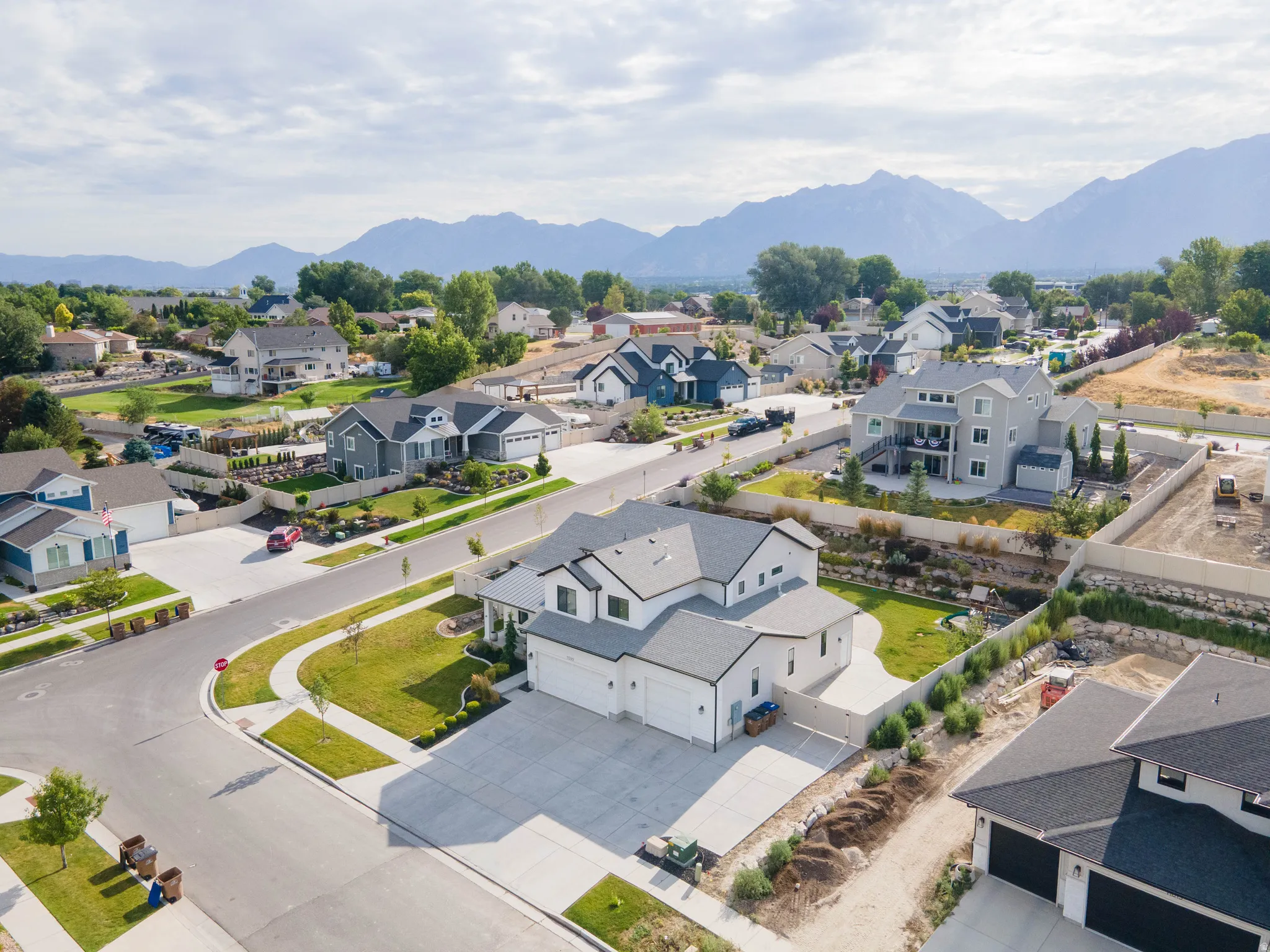 Corner lot property featuring a two-story residence with a light gray exterior, white trim, and an attached 5-car garage