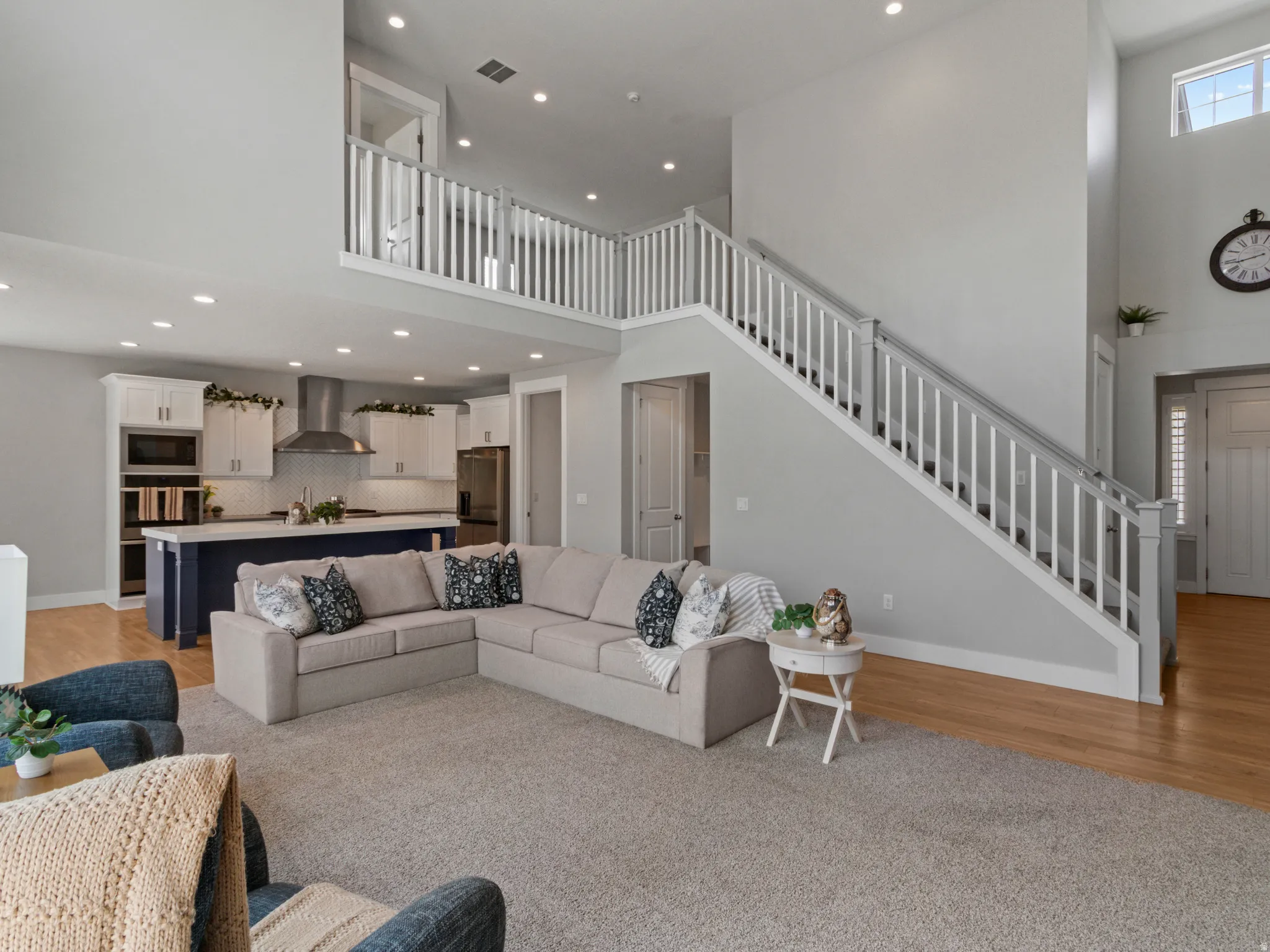 Two-story living area with high ceilings, recessed lighting, and wood-finish flooring